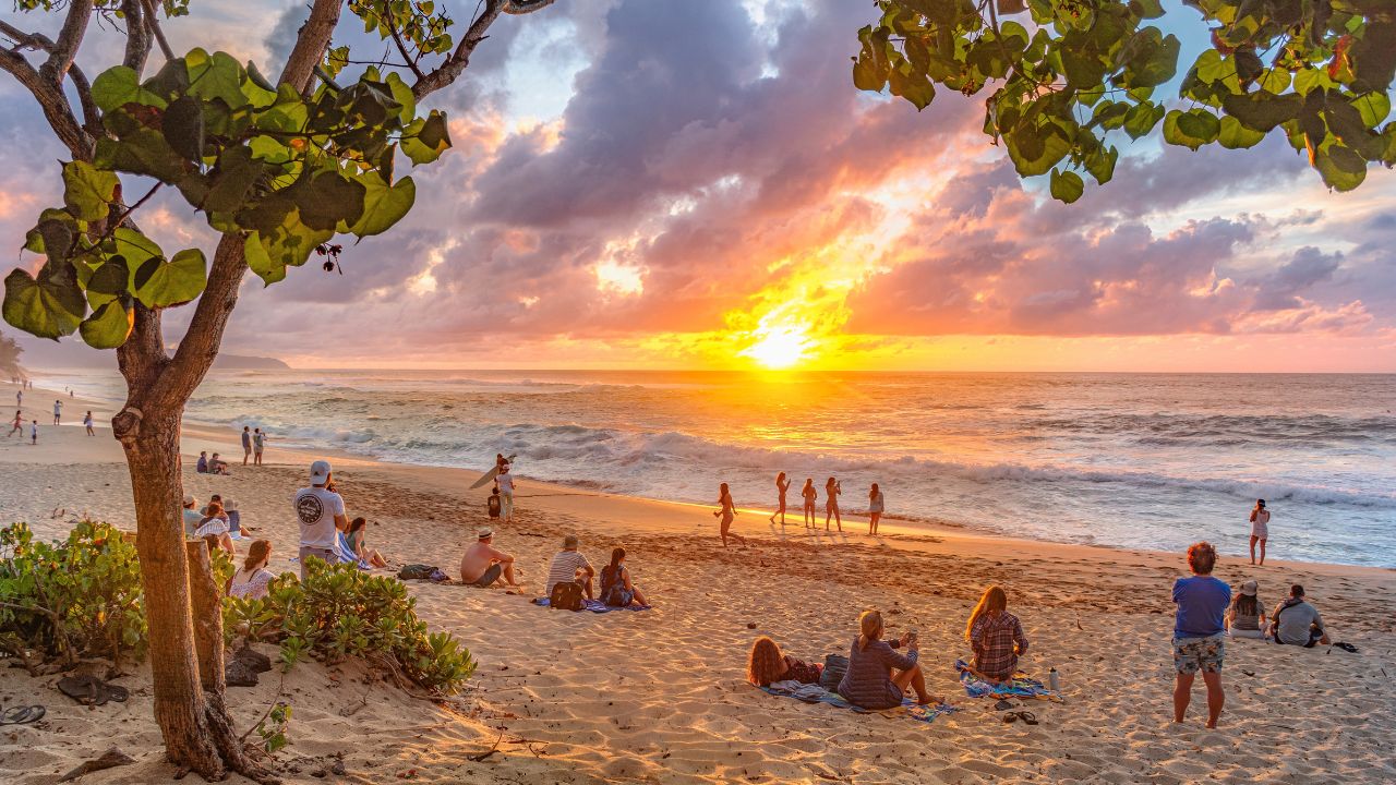 Oahu island, Hawaii, USA- March 22 2022: Tourists enjoying the beautiful sunset at Sunset beach, in the north shore of Oahu island, Hawaii.