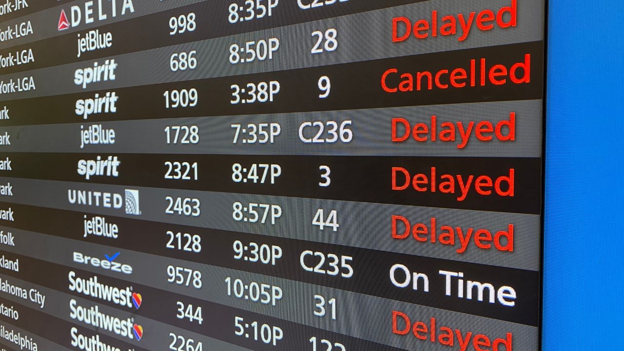 A flight board at Orlando International Airport shows flights cancelled and delayed.