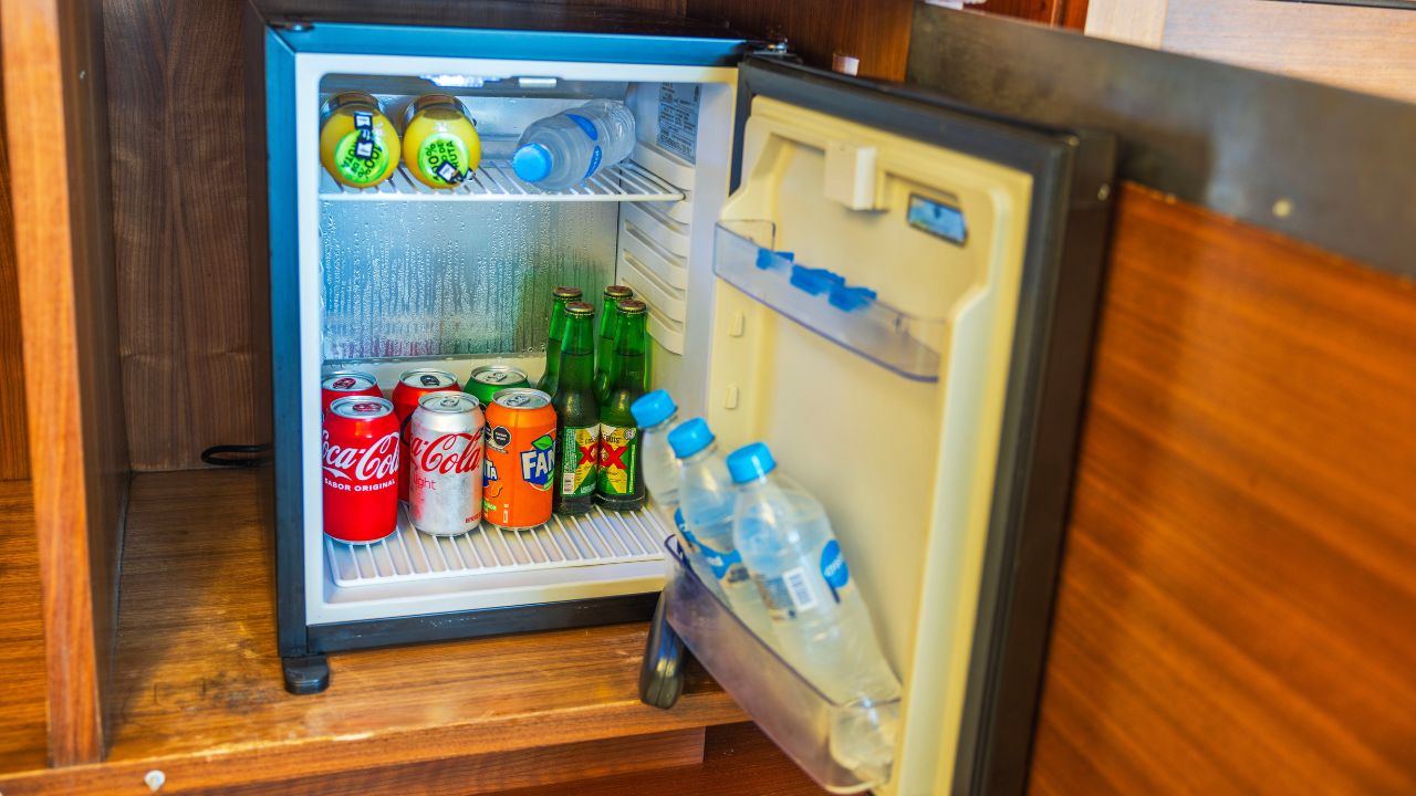 Detailed view of open mini-bar stocked with assorted refreshments in hotel room.