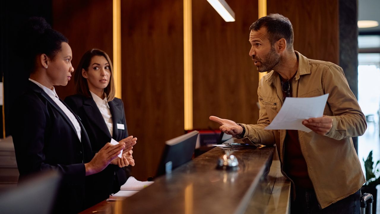Angry guest discussing with managers while complaining about the bill after a hotel stay.
