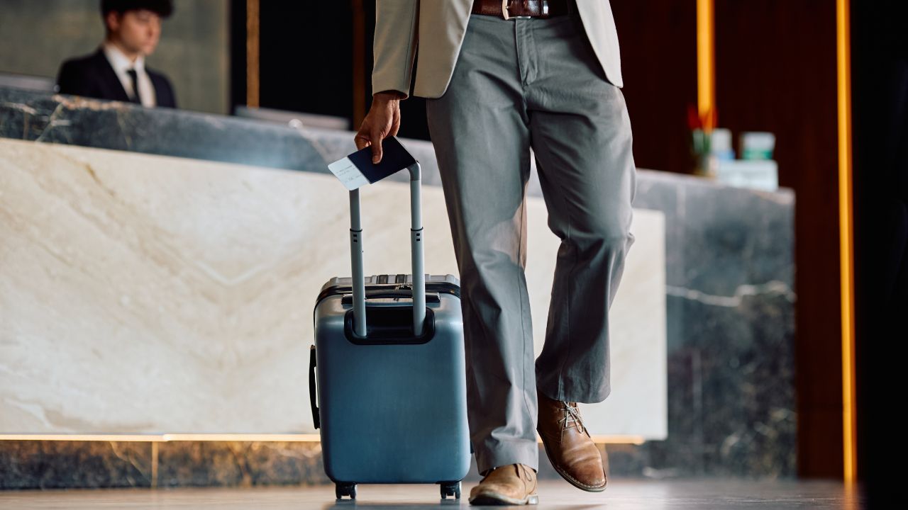 Close up of African American man with luggage and passport in hotel hallway. Copy space.