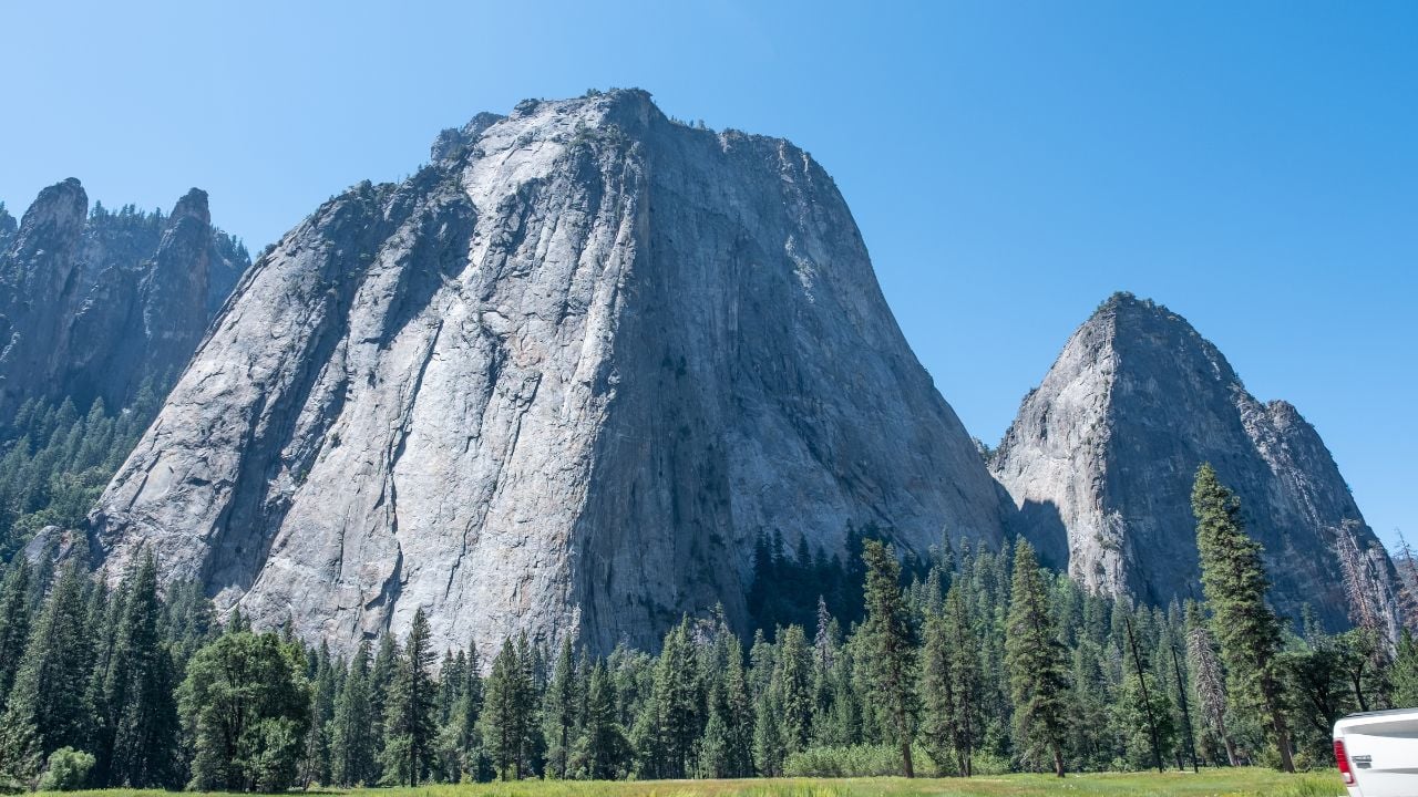 A detailed view of El Capitan’s vertical granite wall fills the frame, illuminated against a deep blue sky at Yosemite’s Tunnel View