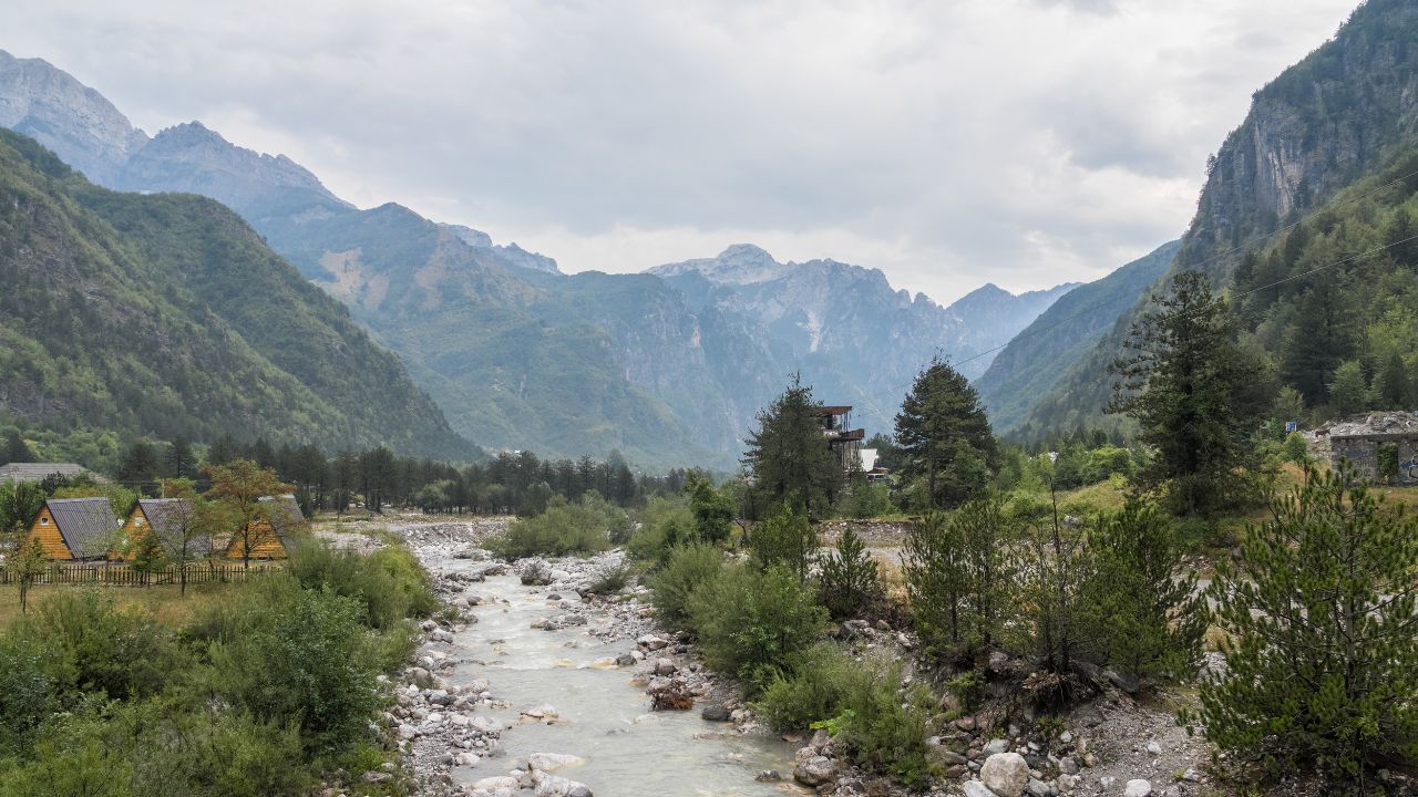 Theth, Albania - August 18 2024: Breathtaking view of the Albanian Alps and river Lumi i Thethit streaming through village Theth, showcasing dramatic mountain landscapes and untouched natural beauty.