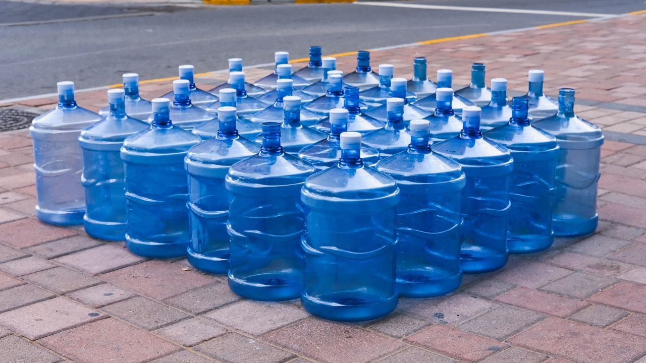 Bottled drinking desalinated water delivery in UAE. Empty refillable plastic drinking water bottles placed outside residential building for pickup.