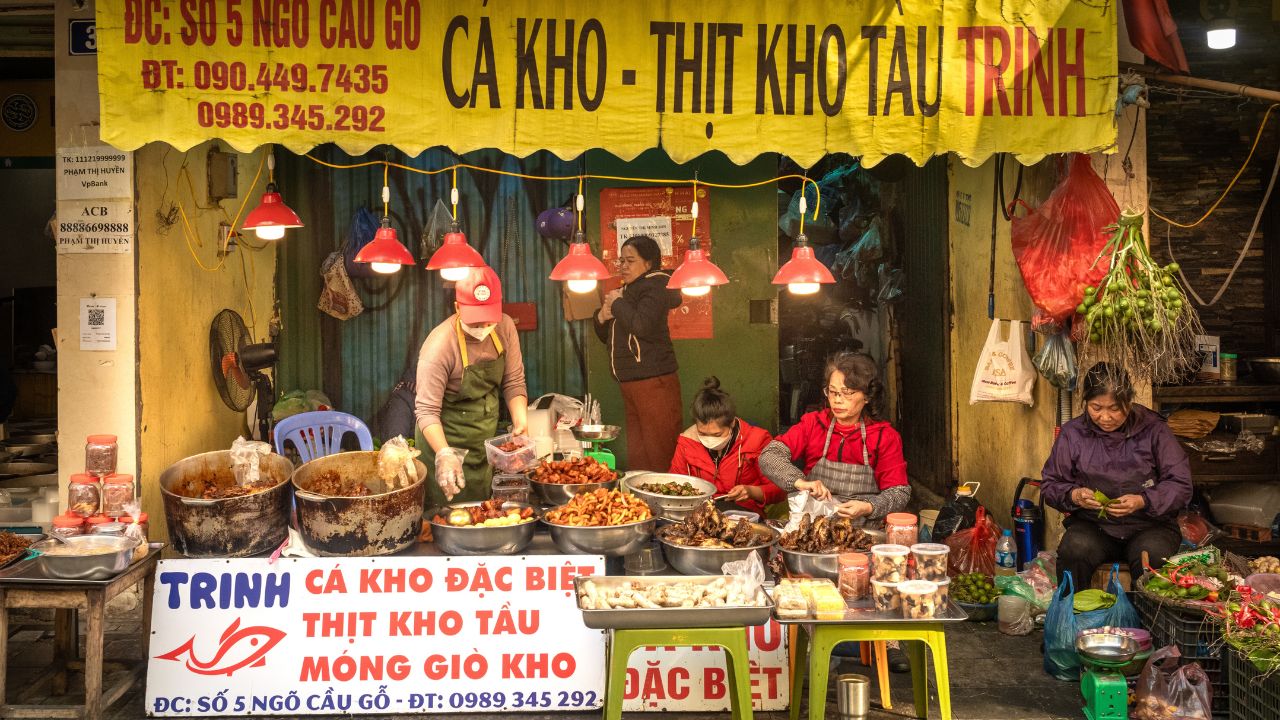 Hanoi Vietnam - Dec 22 2022: Vietnamese women prepare braised fish and pork and other dishes at a take away cooked food shop in the Old Quarter of Hanoi, Vietnam.