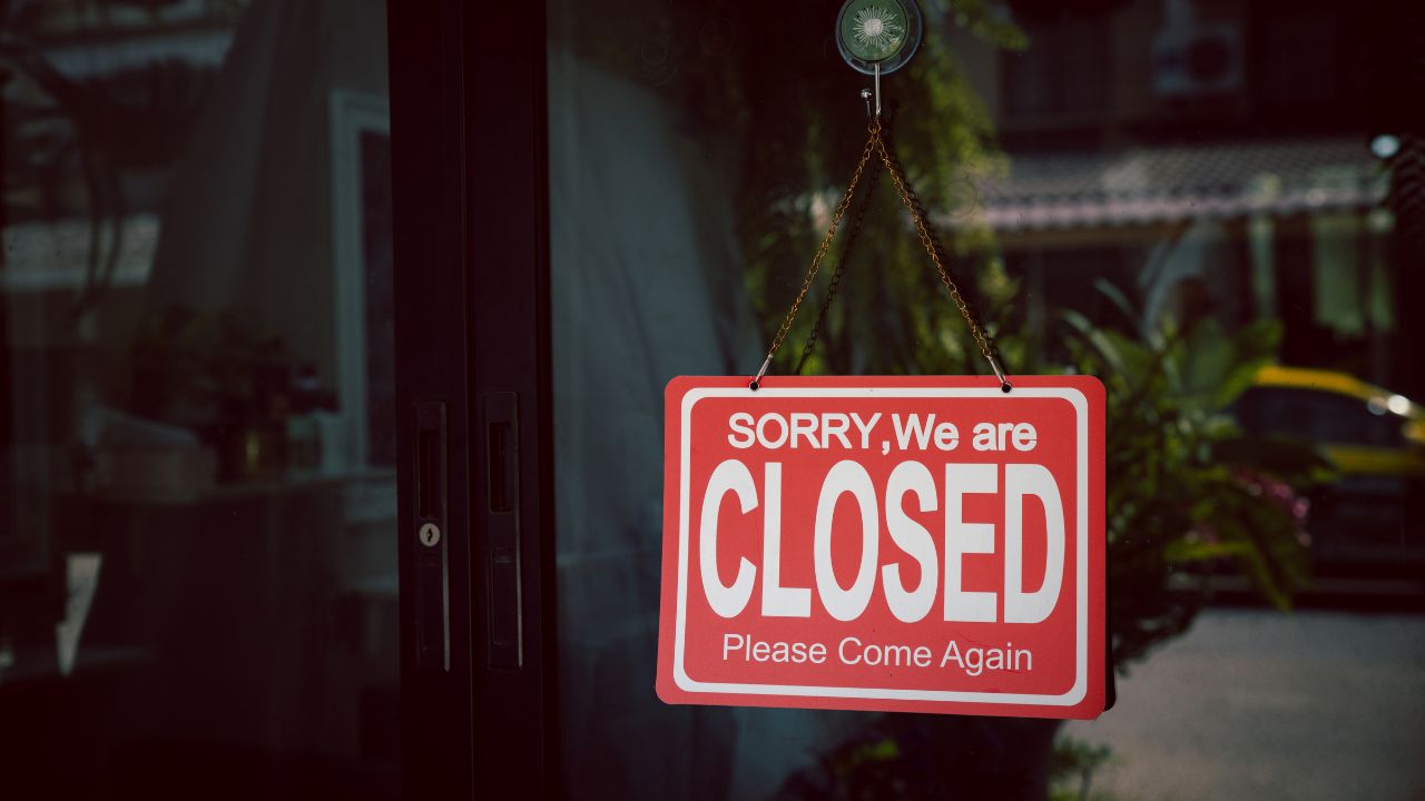 Close sign hanging on the glass door. The white word
