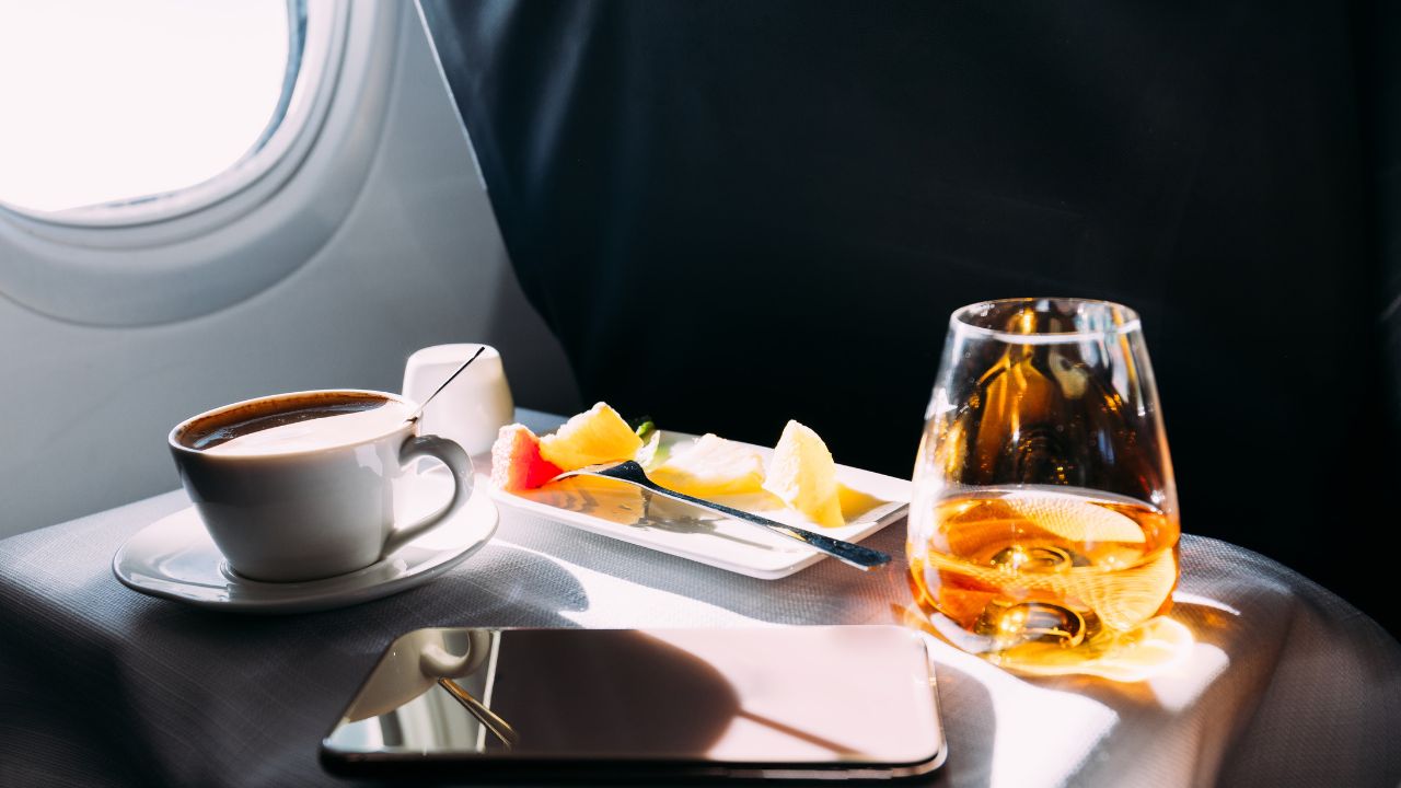 passenger table in airplane with drinks, snacks and digital tablet