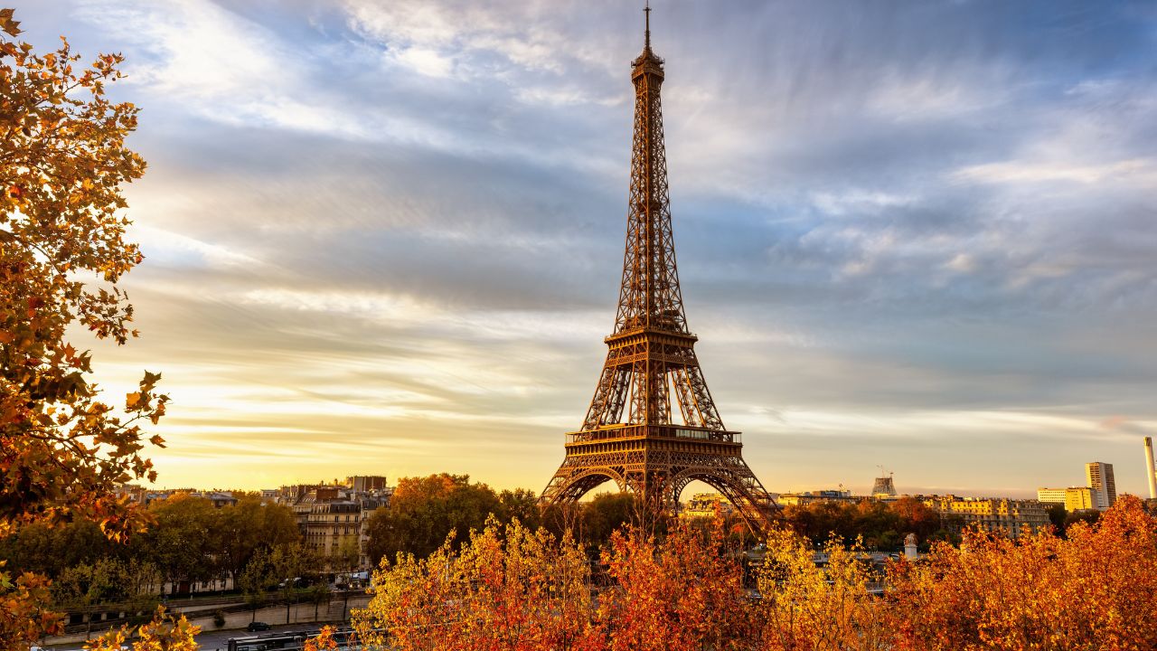 Beautiful autumn sunrise view of the Eiffel Tower in Paris, France, with golden sunlight and colorful leaves