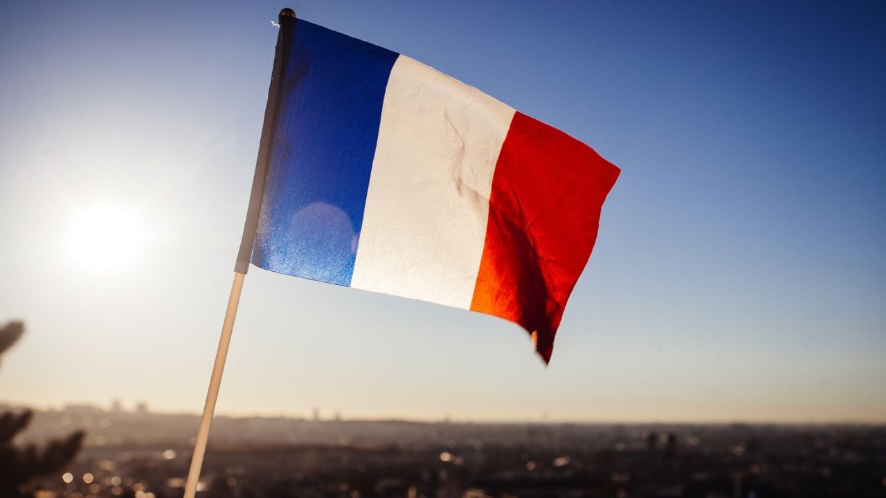 The Flag of France on background of the view of Paris from Sacre Coeur Basilica in France in sunset tima