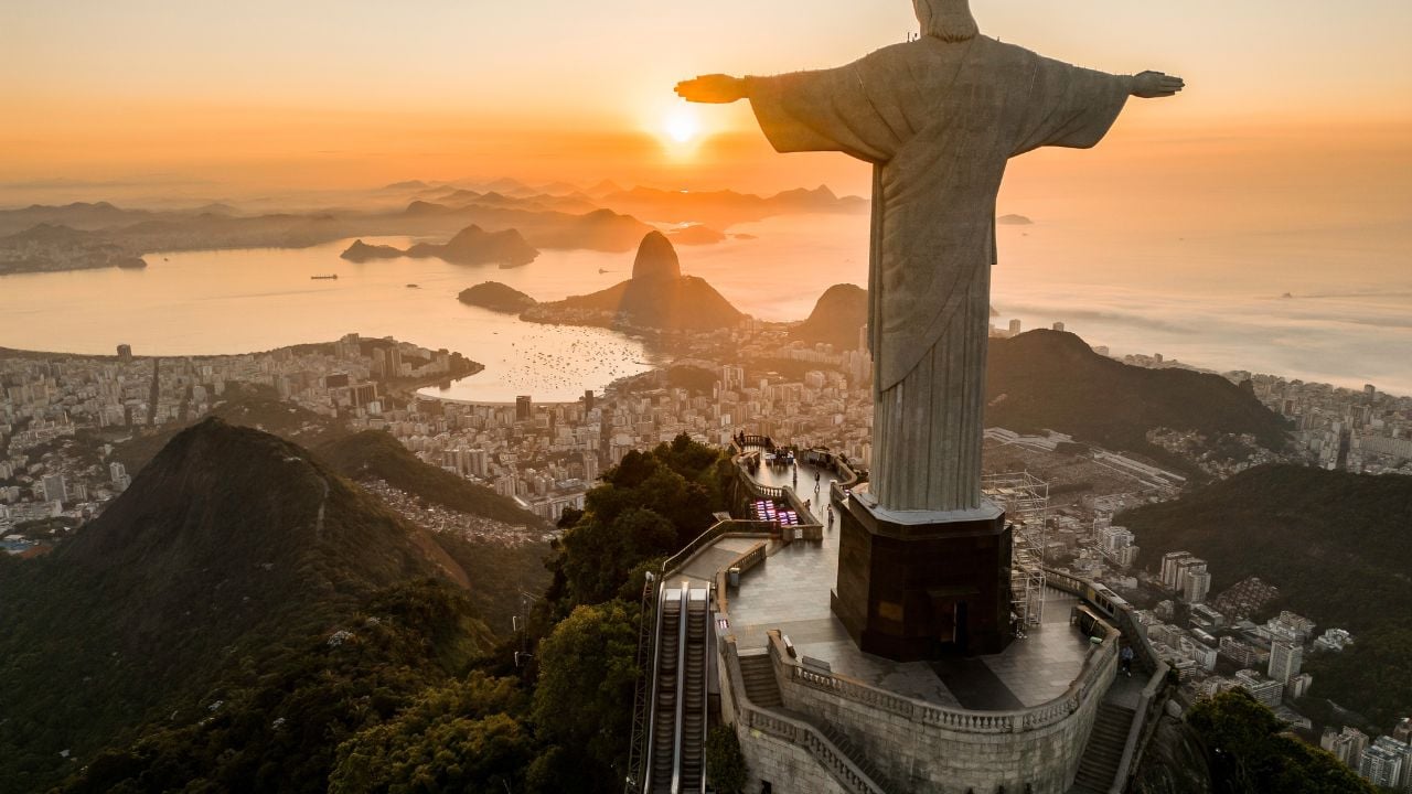 Rio de Janeiro, Brazil - March 21, 2023: Christ the Redeemer statue on top of the Corcovado Mountain with the Sugarloaf Mountain in the horizon on sunrise.