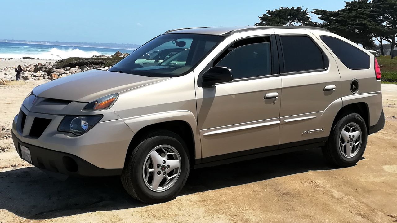 Grey Pontiac Aztek front angle view parked near a beach