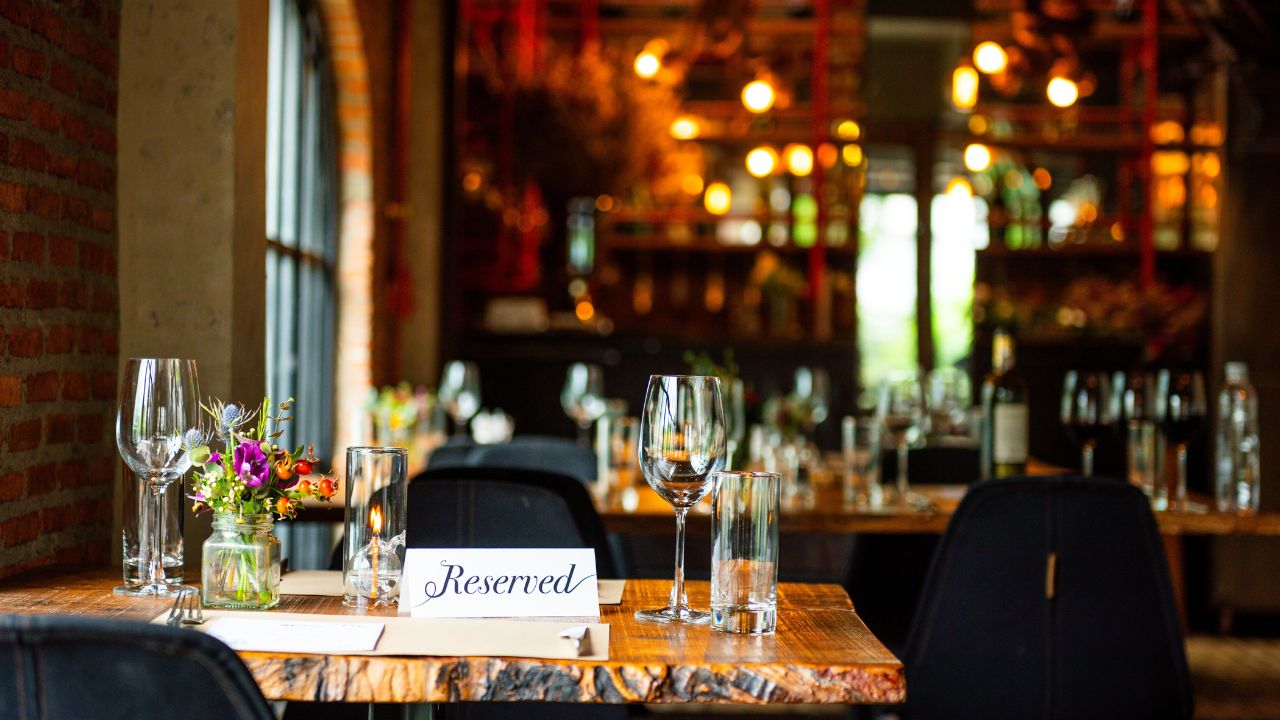 Cozy restaurant with reserved sign on table, elegant decor, and warm lighting. Reservation sign on table in cozy restaurant. Restaurant reservatin sign on table.
