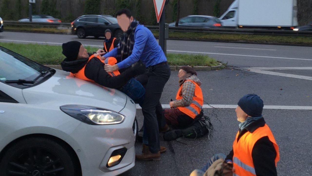 Driver confronting protesters on the road.