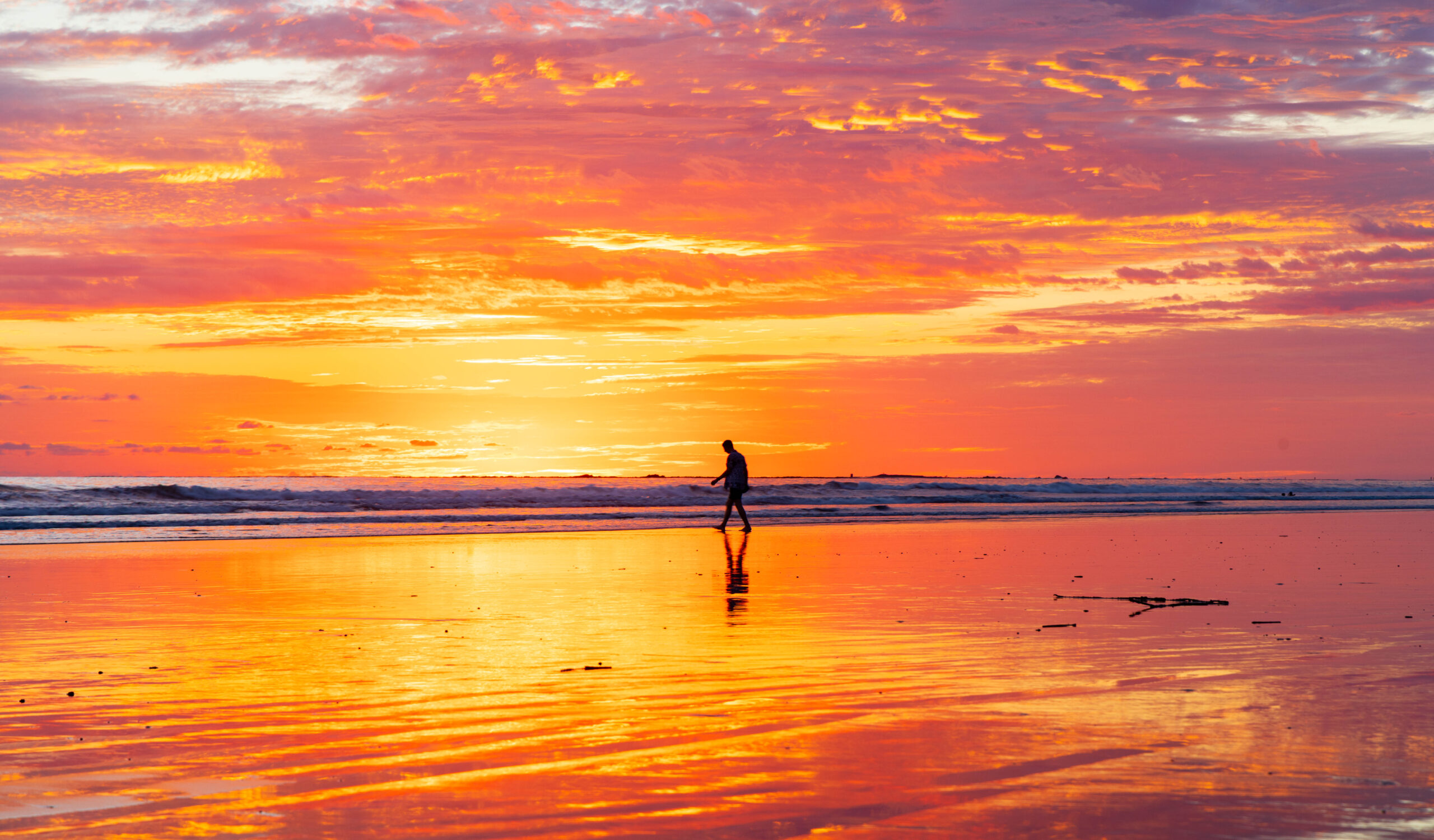 A man walks on the beach at sunset in Uvita.