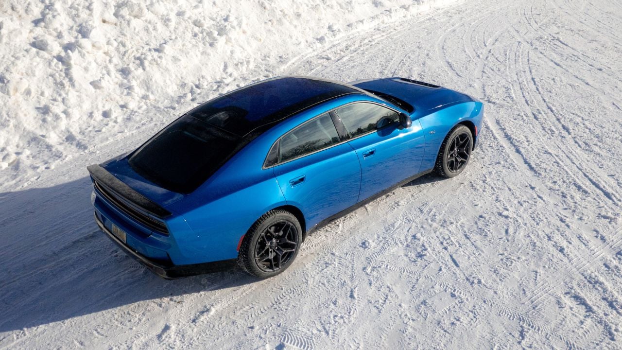 Top rear angle view of a Blue SIXPACK-powered 2026 Dodge Charger R/T parked in the snow