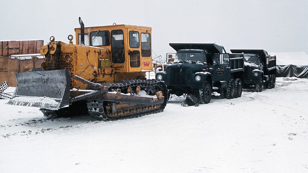 Bulldozer pulls two dump trucks, Alaska.