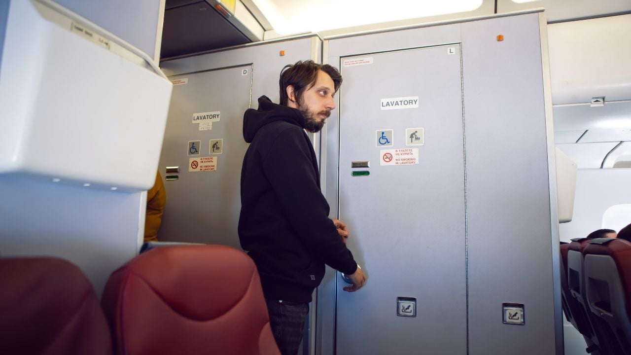 man in black clothes goes to the toilet on the plane