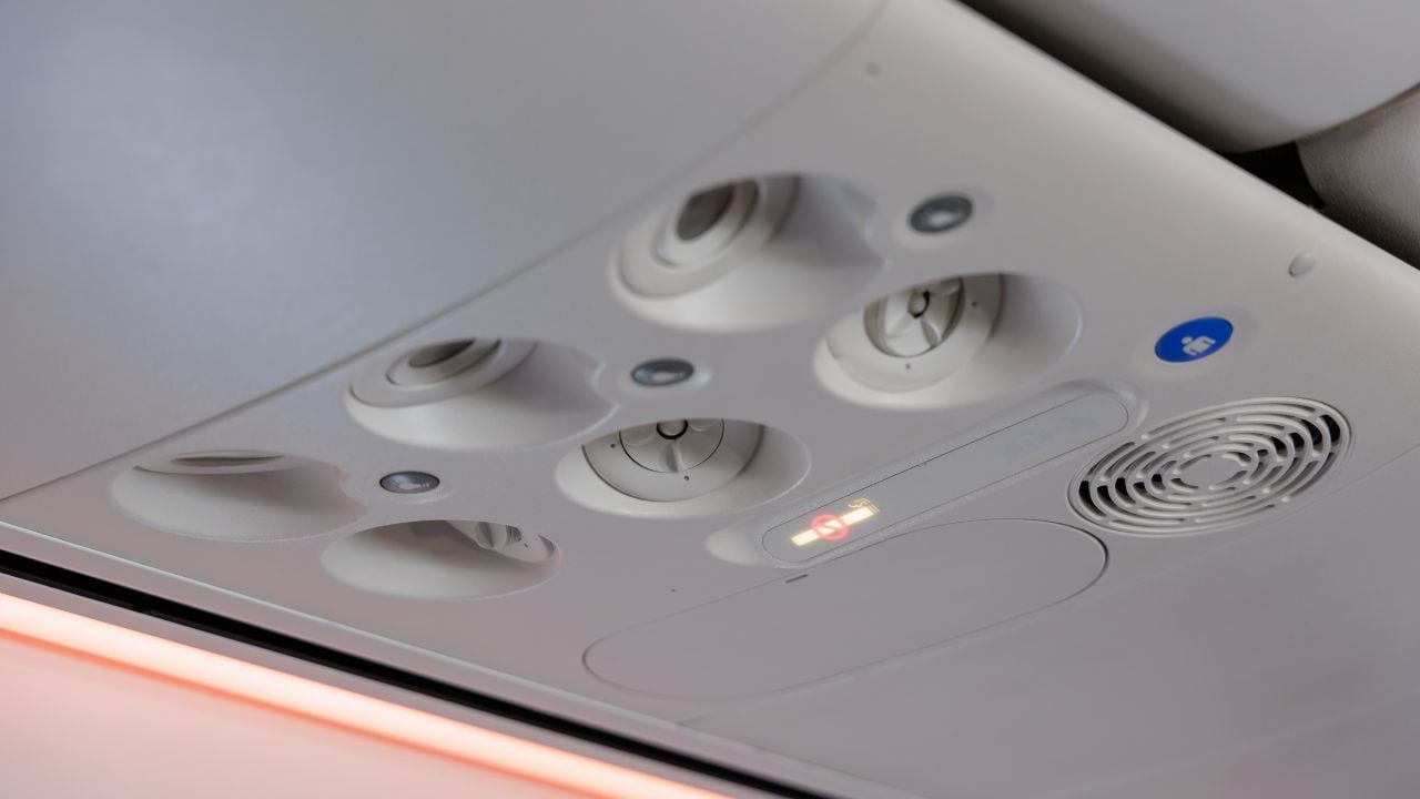 Air conditioning vents above an airplane seat.