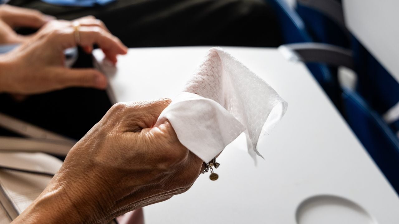Air travel passenger preparing anti-bacterial wet wipes to sanitize personal space in air plane