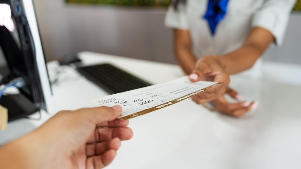 Boarding pass handing moment by airline ground staff during check-in. Close-up of hands exchanging travel document, highlighting smooth airport procedure and professional passenger assistance.