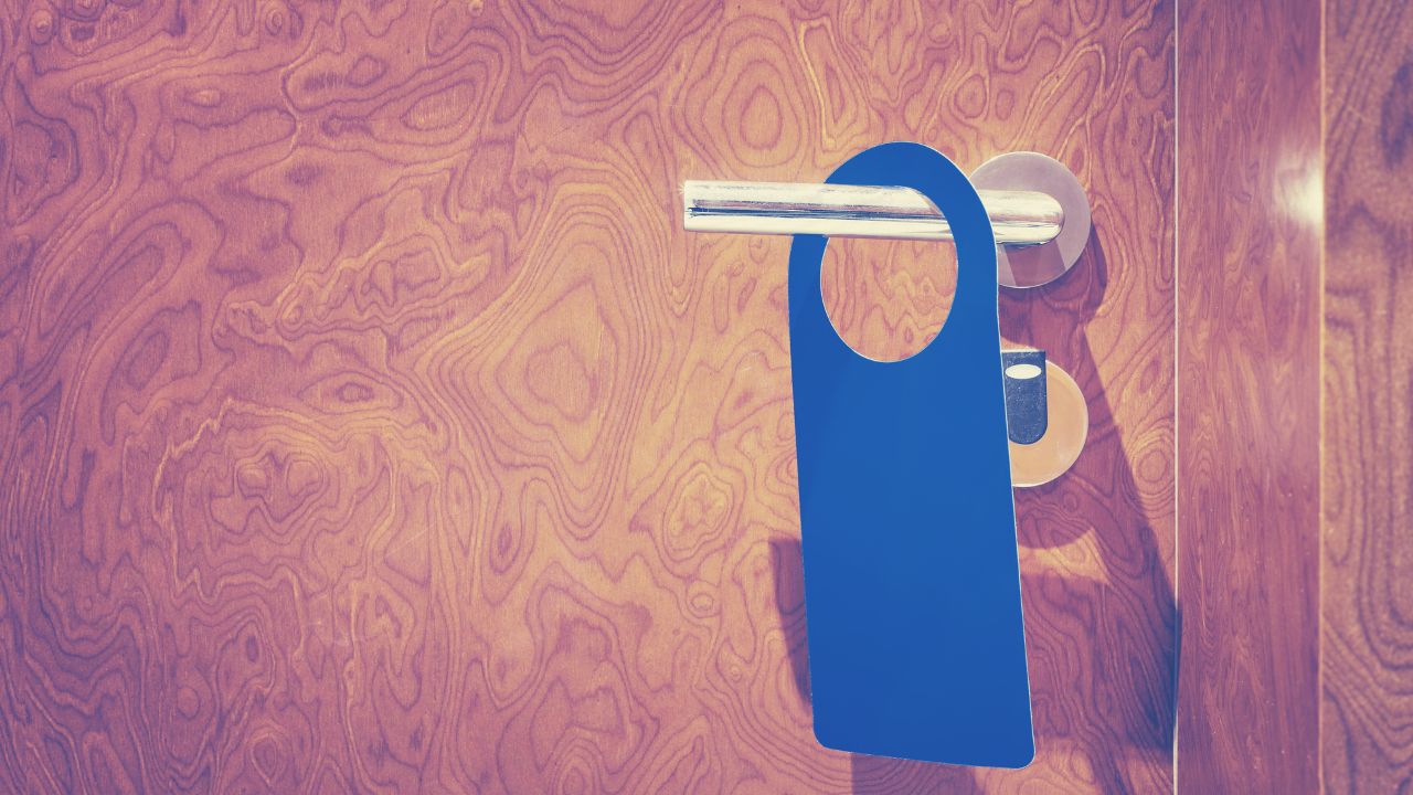 Vintage toned hotel room closed door with hanger, copy space for inscription like do not disturb or make up room.