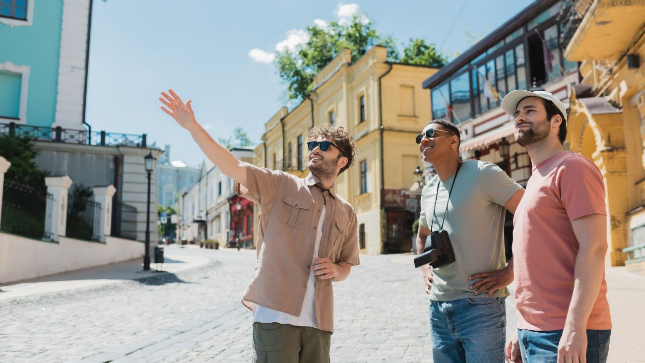 tour guide in sunglasses pointing with hand during excursion with interracial tourists on Andrews descent in Kyiv