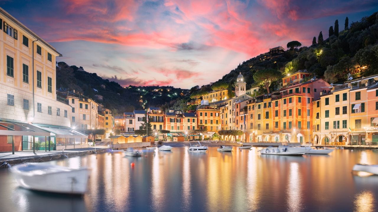 Aerial view of Portofino, a picturesque seaside village with colorful houses and boats in the harbor, surrounded by lush green hills, Liguria, Italy.