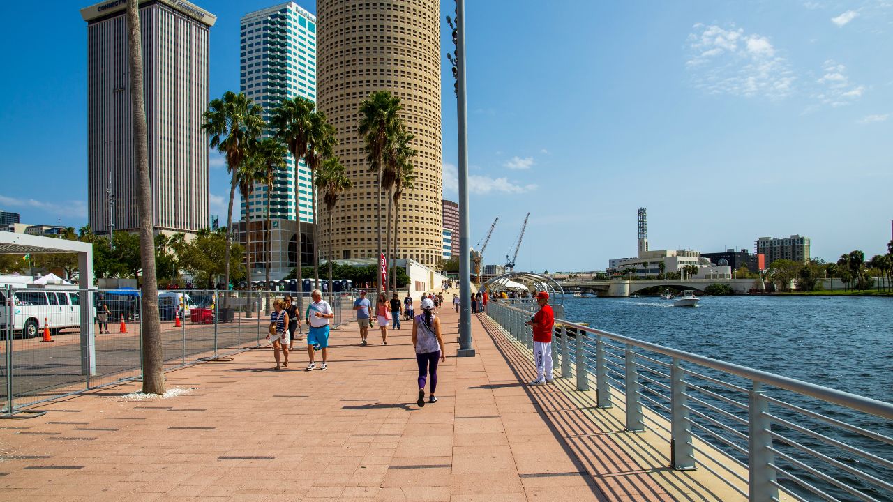Tampa Florida USA - 3 6 2025: People walking along the Tampa Riverwalk with boats sailing along the Hillsborough River in Tampa Florida USA