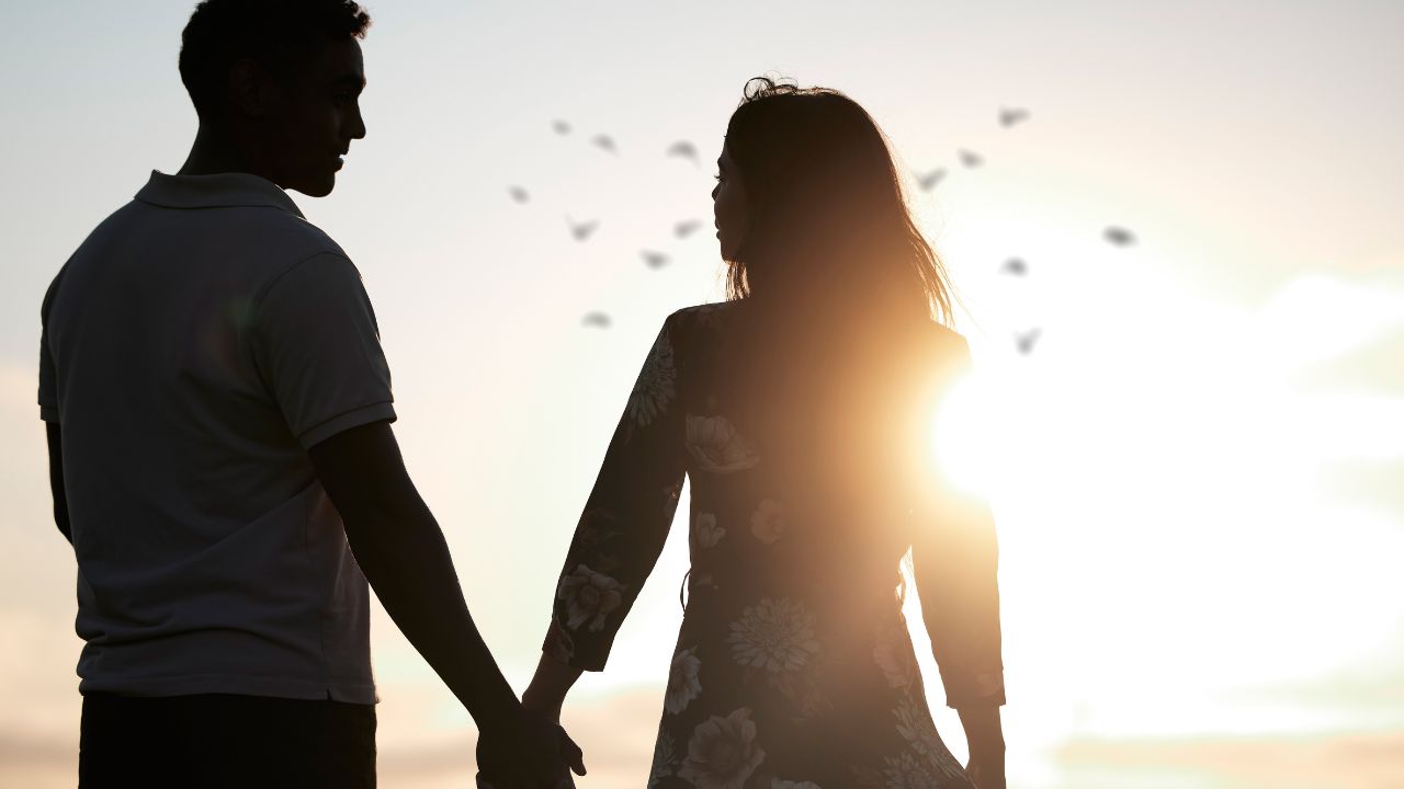 Couple, silhouette and holding hands at romantic, destination, holiday or honeymoon in summer at sunset on vacation on date. Woman, man and relationship in love or together, memory and travel on trip