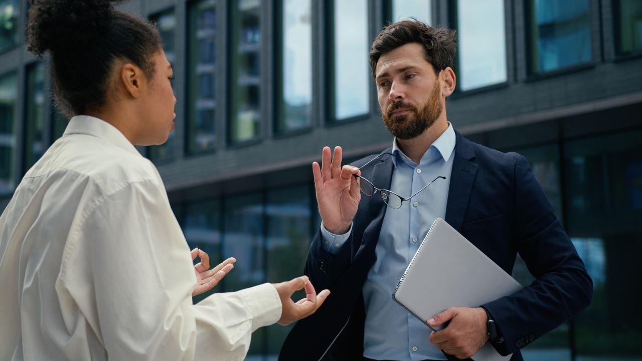 Angry African American woman businesswoman female leader CEO boss irritated talk to Caucasian man businessman male manager stressed worker lady yelling scolding problem business work conflict in city