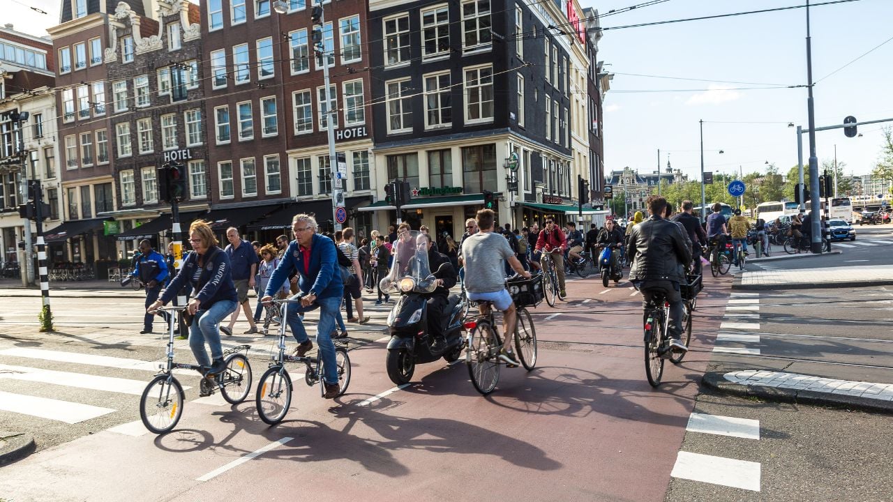 AMSTERDAM, THE NETHERLANDS - JUNE 16, 2016: People riding bicycles in historical part of Amsterdam in a beautiful summer day, The Netherlands on June 16, 2016