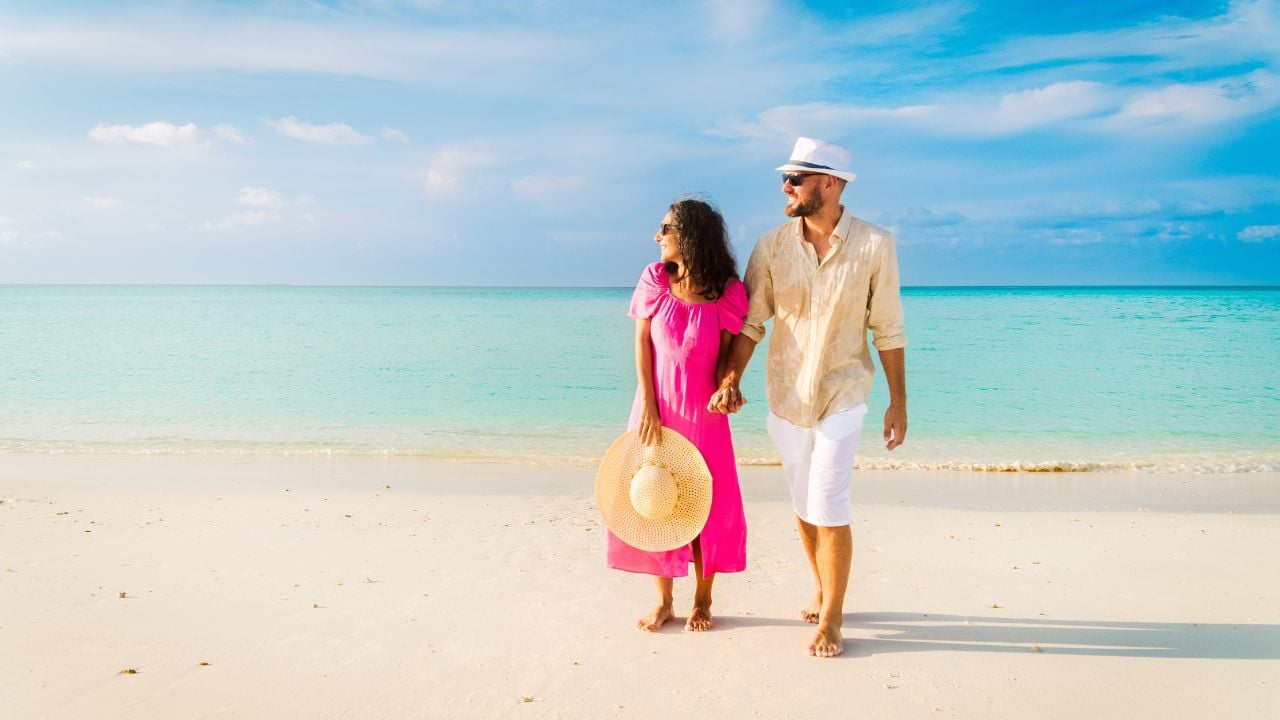 Beautiful traveler couple walks in tropical beach on sunrise watch sunrise in Maldives island Fulidhoo. Romantic holidays vacation