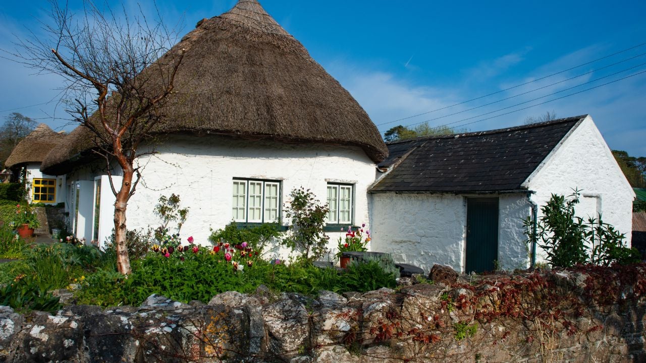 Traditional Irish cottage behind a stone wall in rural Ireland