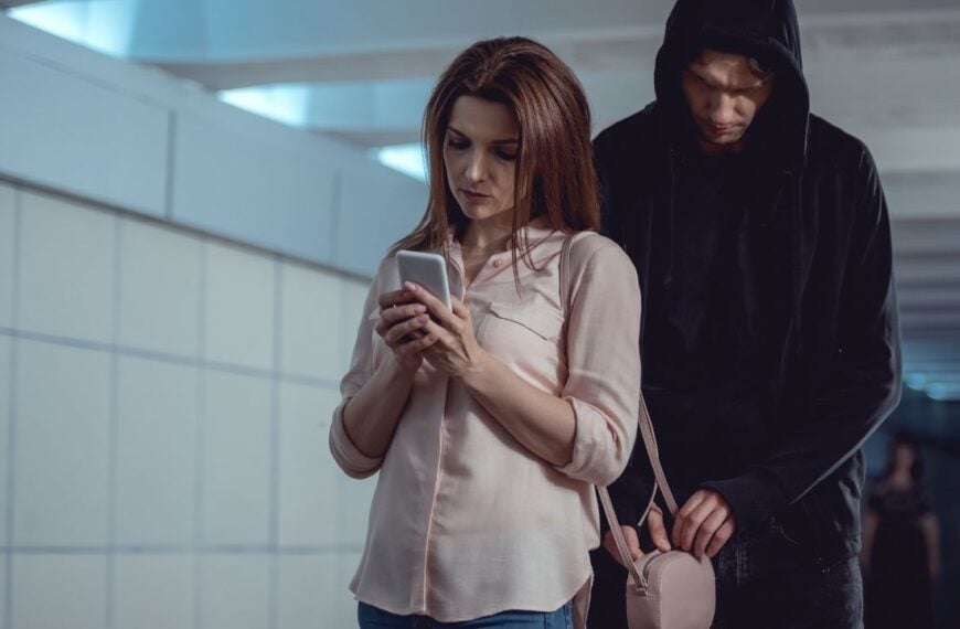 thief stealing money from bag of woman using smartphone in underpass