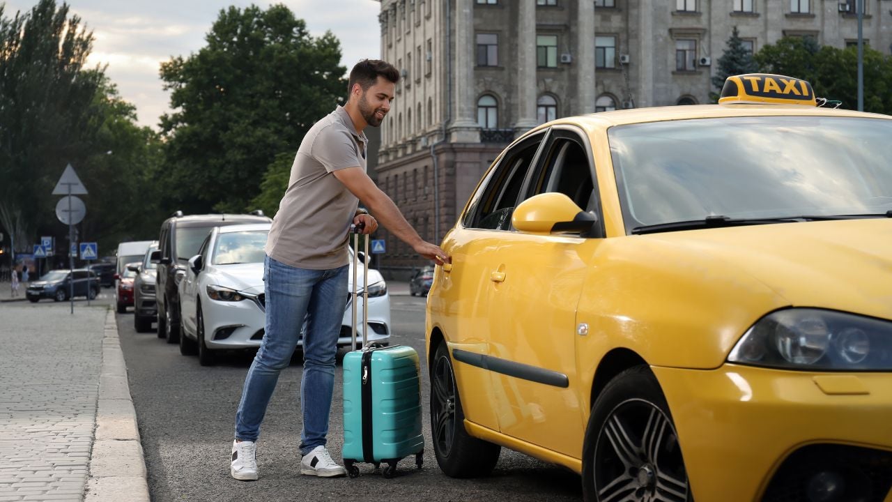 Traveler with suitcase getting into a taxi on a city street
