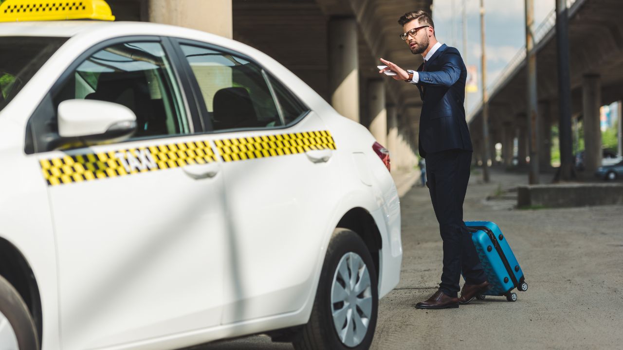 Traveler with smartphone and suitcase looking for a taxi