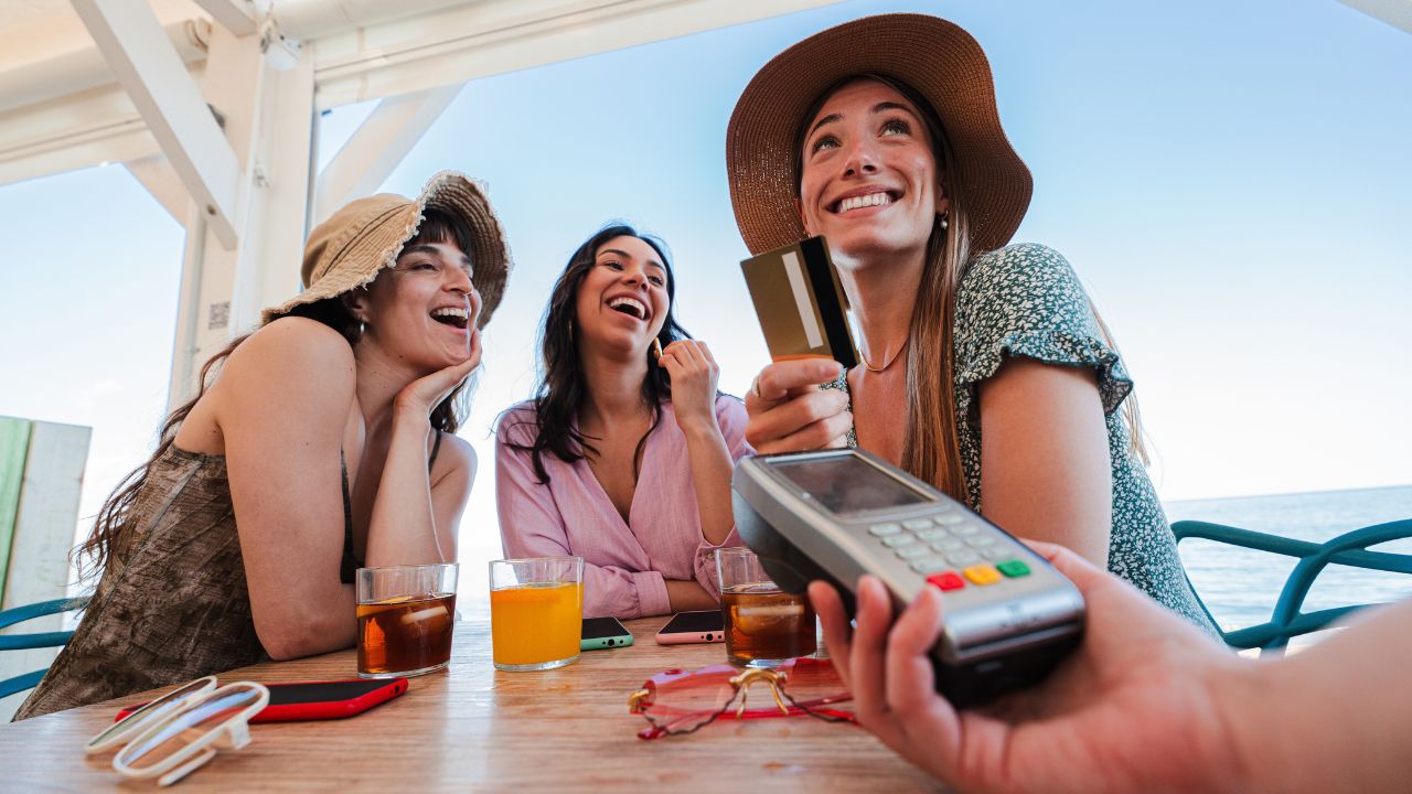 Women paying by card at a beach bar