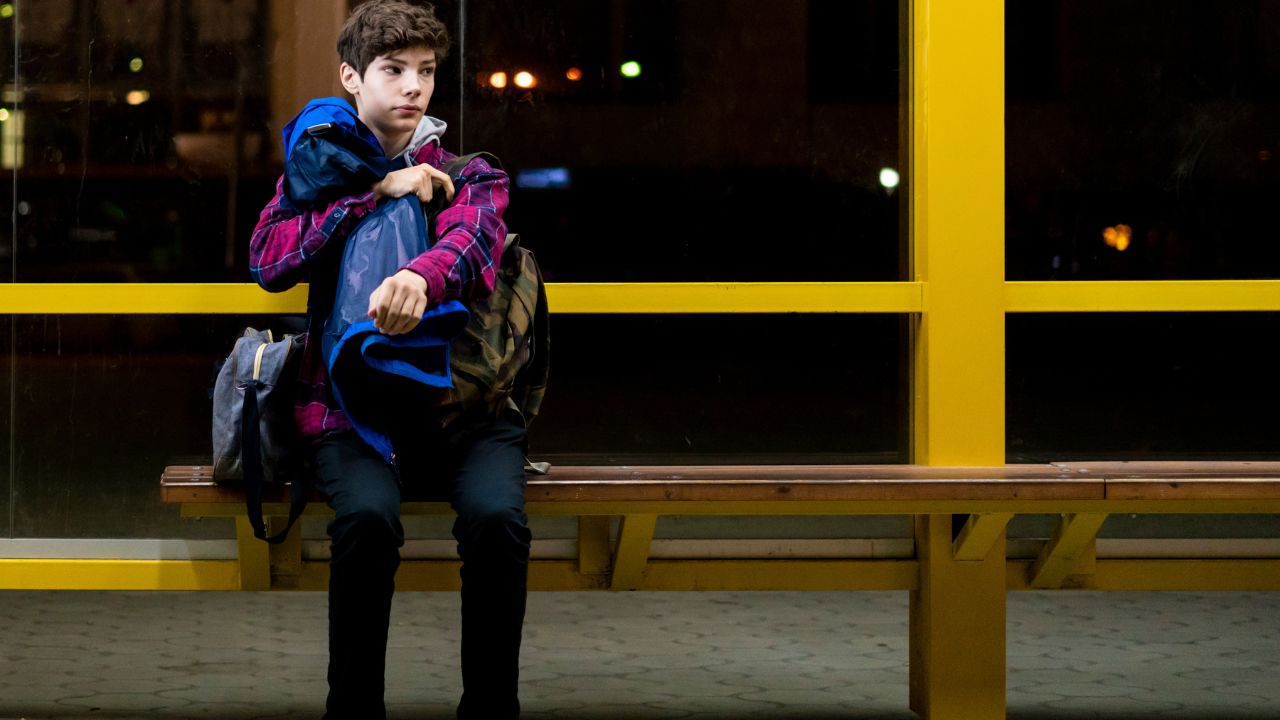Traveler waiting alone at a bus stop at night