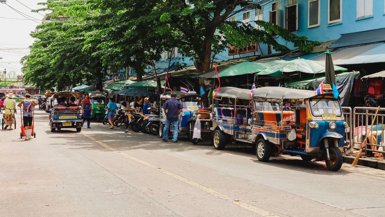 Bangkok, Thailand - August 11 2019 : Tuk Tuk car and motorcycle at Charoen Rat Road. People walking on the road at Wongwian Yai Market.