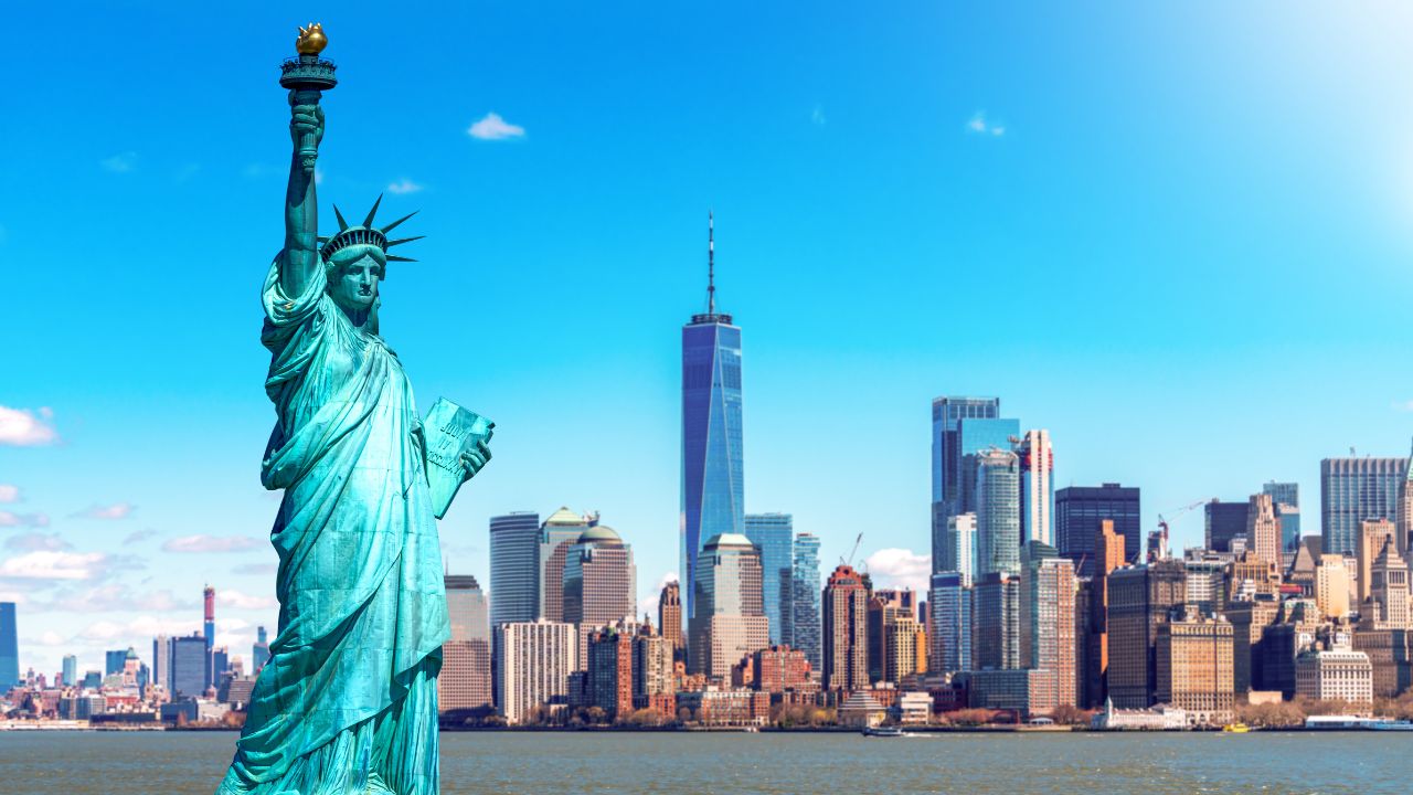 The Statue of Liberty with the One World Trade Center over the Hudson River and New York cityscape background