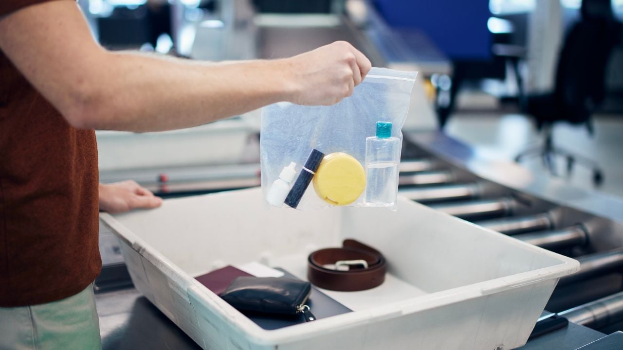 Airport security check before flight. Passenger holding plastic bag with liquids above container personal items.