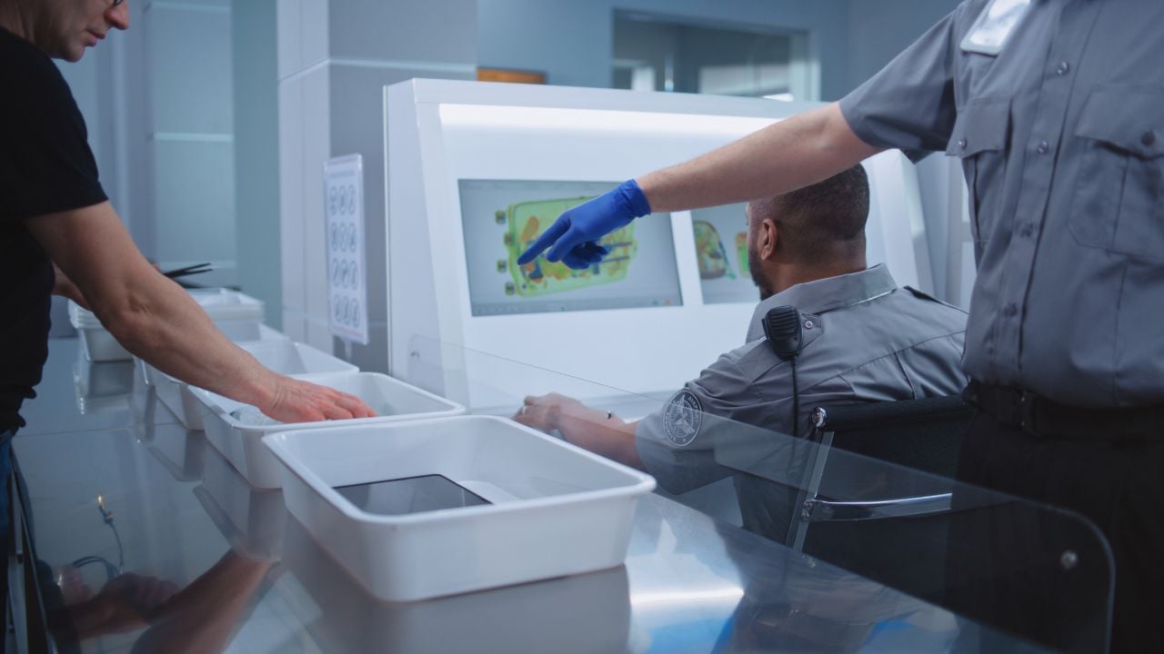 Airport Security Checkpoint during Boarding Flight. Diverse Passengers Put Personal Belongings in Plastic Trays for Screening: Tablet Computer, Phone, Documents. Security Officers Control Procedures.