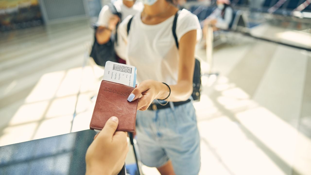 Close up portrait of airport worker giving passport and air ticket to tourist with backpack