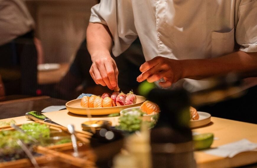 Sushi chef skillfully prepares fresh sushi rolls, showcasing vibrant ingredients and meticulous technique in a lively culinary environment.