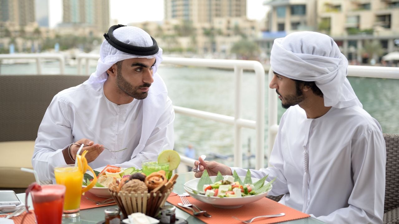 Two young Emirati arab friends talking in a restaurant