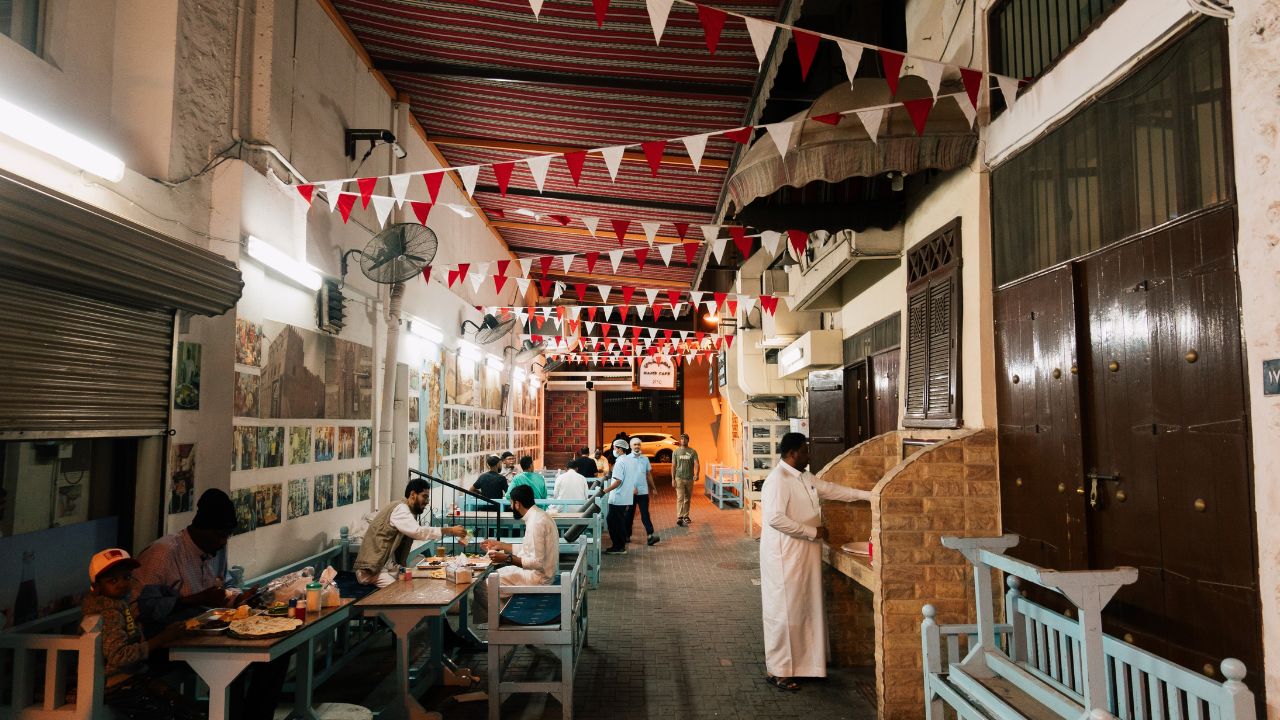 Manama, Bahrain - December 13, 2022: diners sit in the outdoor section at Haji's Traditional Cafe in a narrow street in the city center
