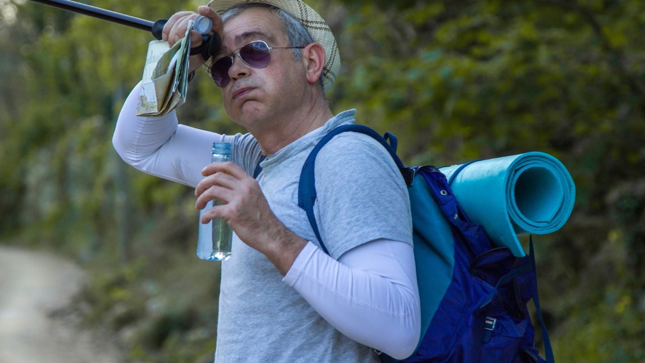 tired mountaineer man hiking or trekking up the mountain making a drinking break