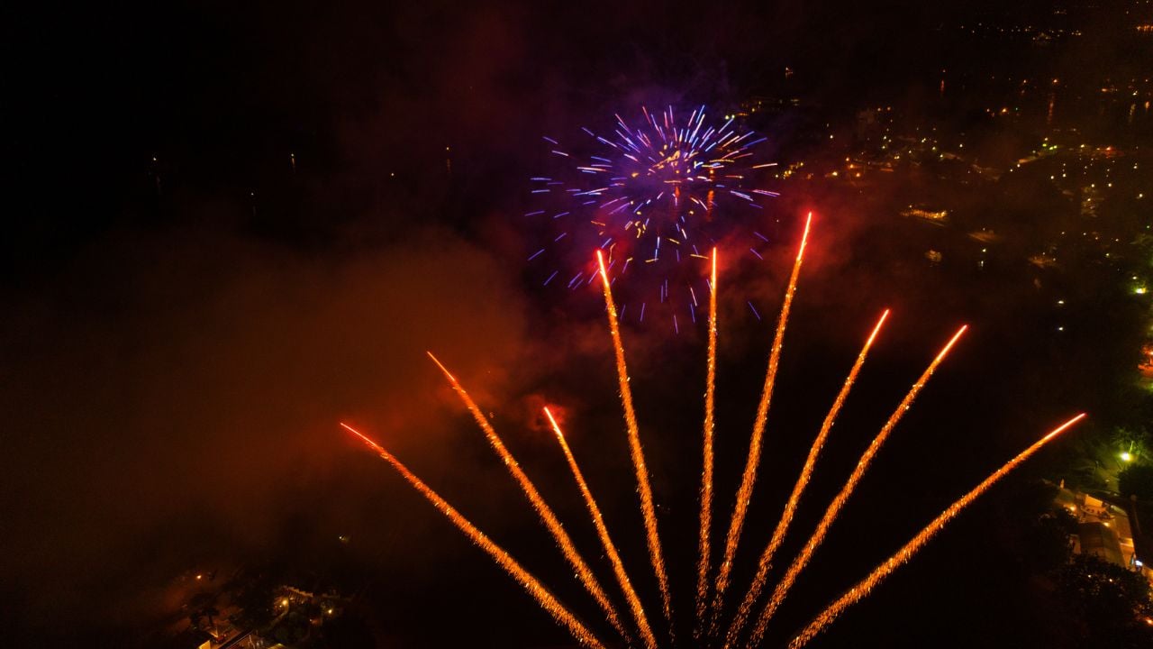 A bright pink flash of fireworks over a city at night. Shooting with the drone. Selective focus. Motion blur. Copy space