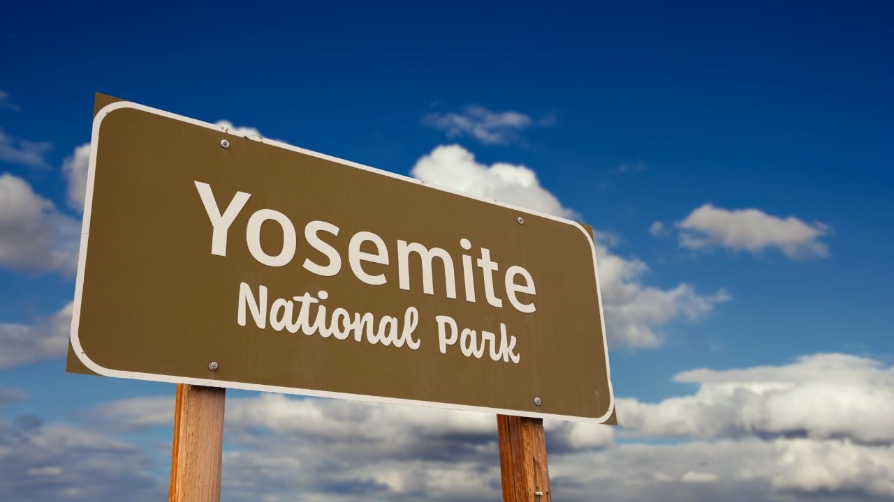Yosemite National Park (California) Road Sign Against Blue Sky and Clouds.
