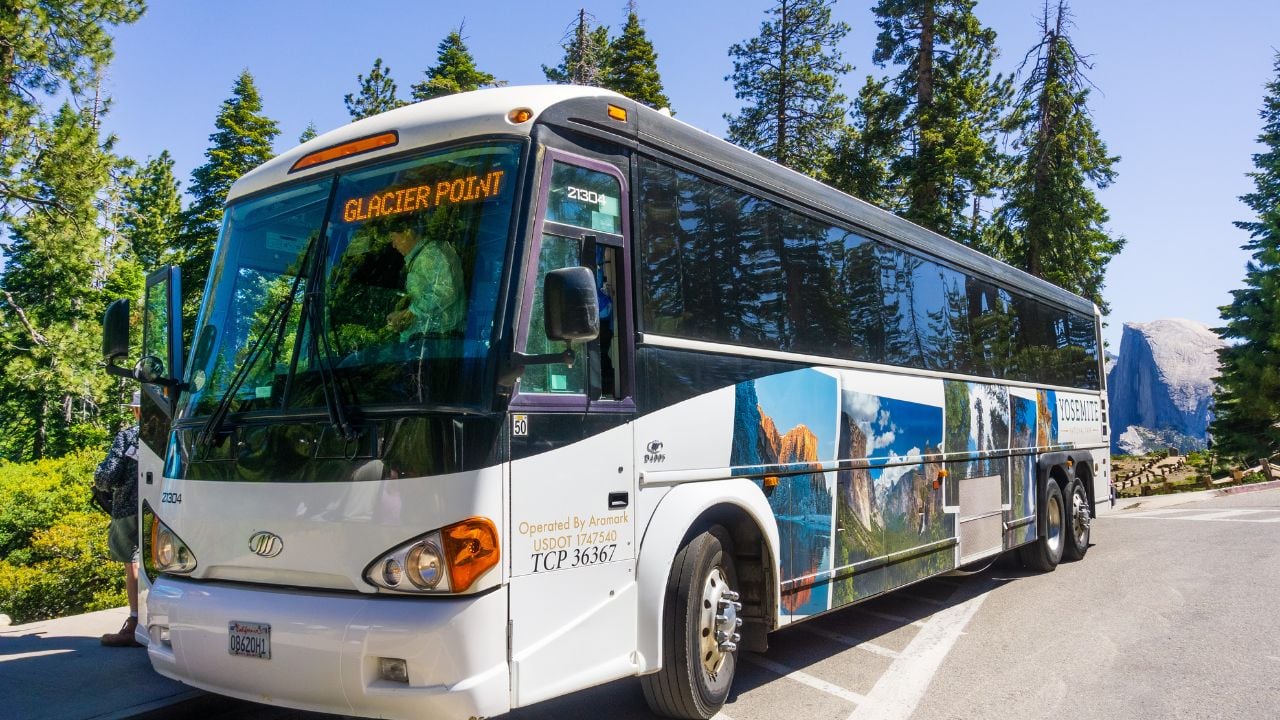 June 27, 2019 Yosemite National Park / CA / USA - The Yosemite Glacier Point guided tour bus, operated by Aramark, available from late May to early November; Half Dome visible in the background